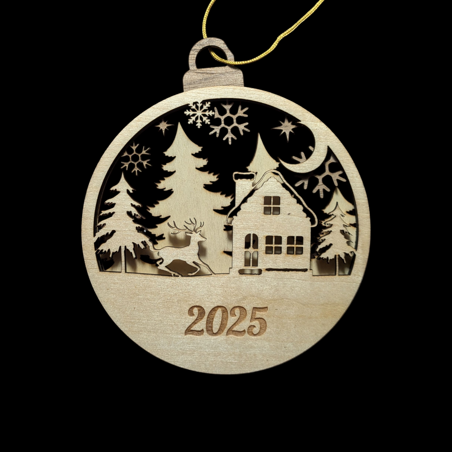 Wooden Christmas ornament with a house, trees, and deer design, featuring the year 2025 on a black background.