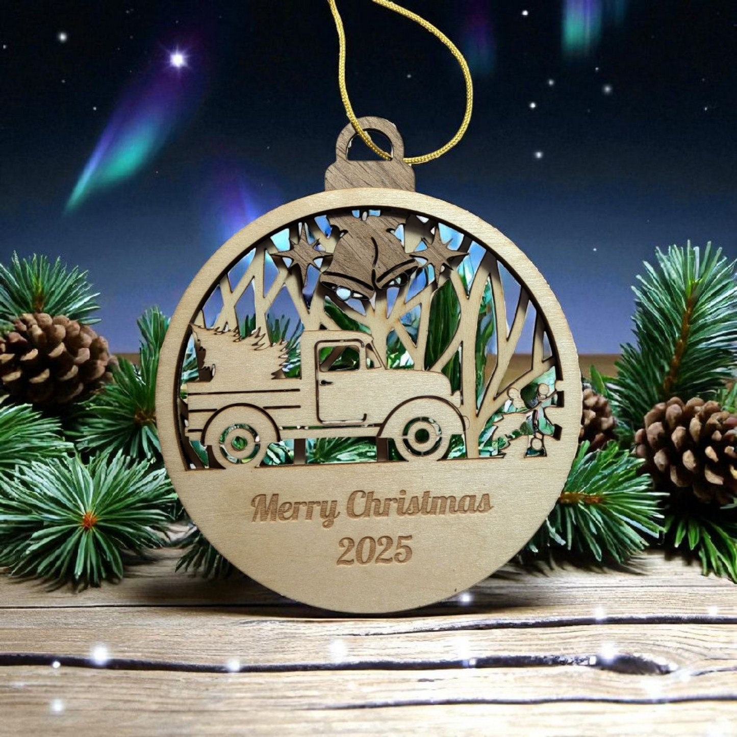 Wooden Christmas ornament with truck and tree design, 'Merry Christmas 2025' text, surrounded by pine branches and cones.