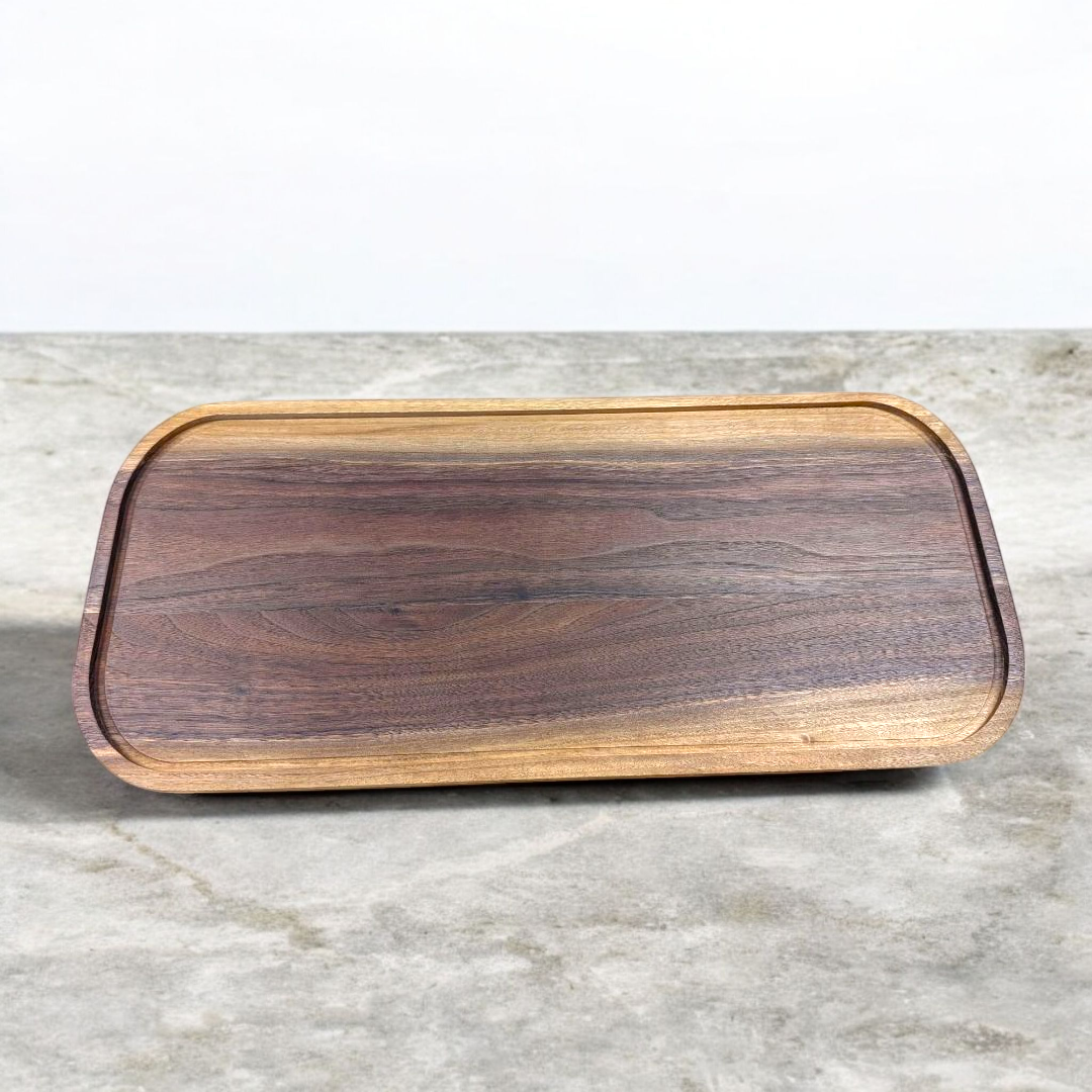 Wooden cutting board with a dark brown finish on a light gray surface
